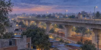 A city flyover at blue hour with distant lit windows