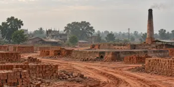 A brick kiln field and a distant line of trees under haze